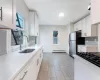 Kitchen featuring stainless steel fridge, backsplash, baseboard heating, sink, and white cabinetry