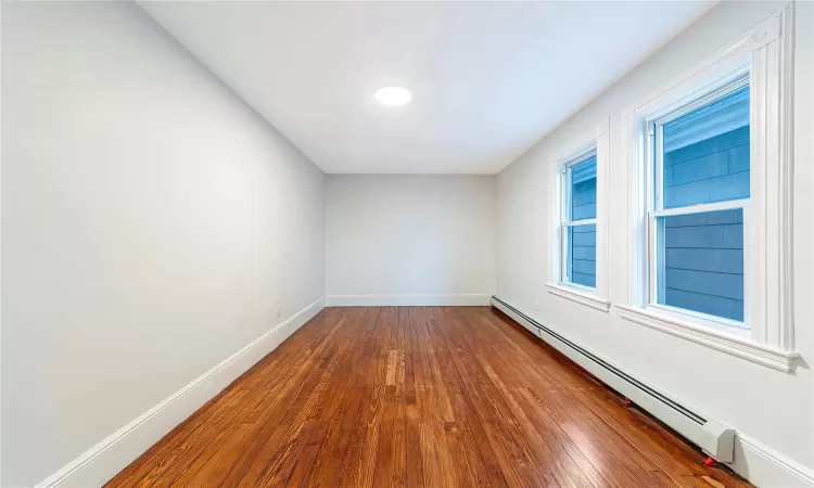 Second Angle of Bedroom #2 with dark hardwood / wood-style floors and a baseboard radiator