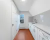 Kitchen with white cabinetry, sink, a baseboard radiator, hardwood / wood-style floors, and lofted ceiling