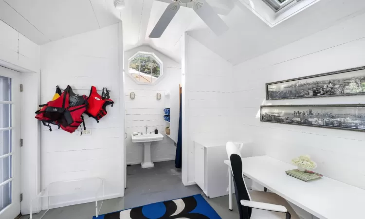 Bathroom featuring vaulted ceiling, wooden walls, and concrete flooring