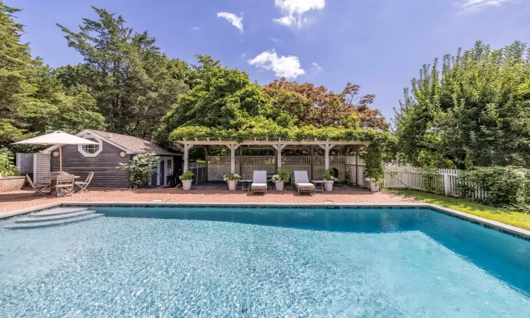 View of pool featuring an outbuilding and a pergola