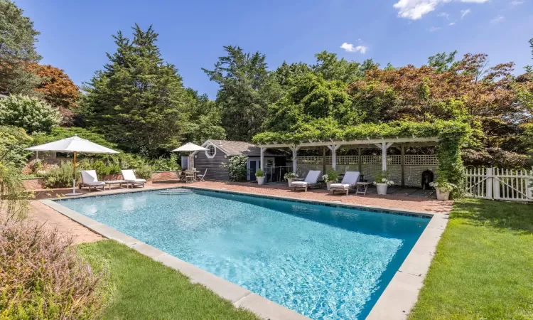 View of pool with a lawn, an outdoor structure, and a patio