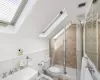 Bathroom with an enclosed shower, a skylight, sink, toilet, and a bidet