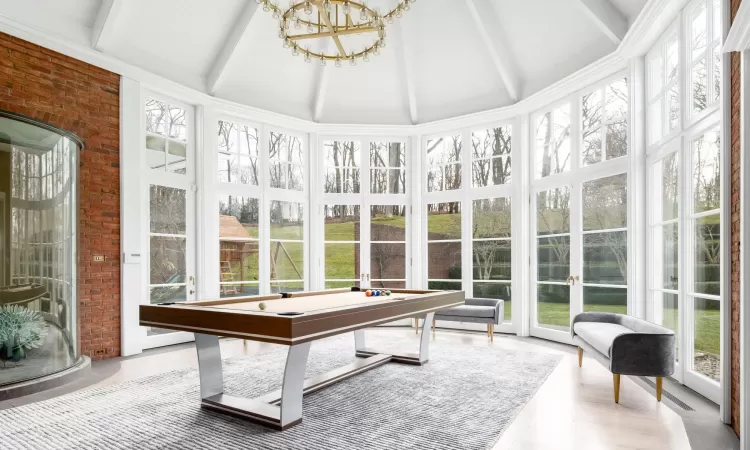 Sunroom featuring a notable chandelier, pool table, and beamed ceiling