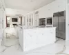 Kitchen with sink, white cabinets, stainless steel built in refrigerator, and an island with sink