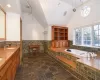 large primary bathroom with vanity, high vaulted ceiling, and a relaxing tub