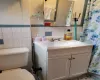 Bathroom featuring vanity, tile walls, and toilet