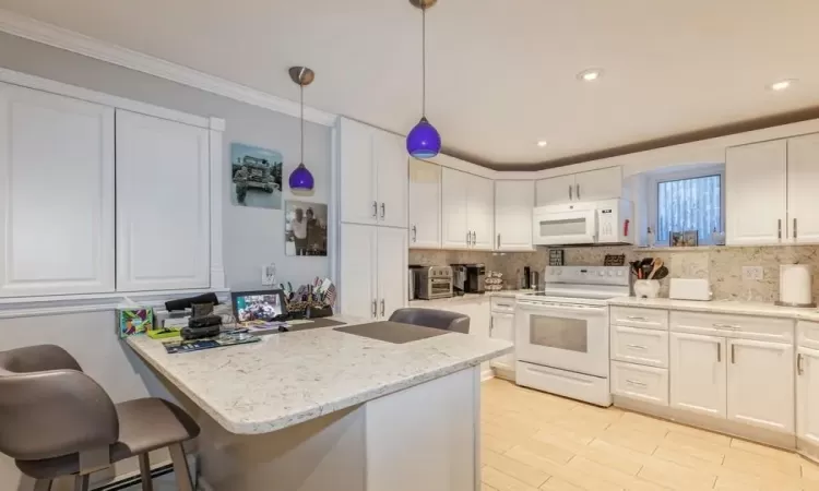 Kitchen featuring decorative light fixtures, white cabinets, a kitchen breakfast bar, light stone counters, and white appliances