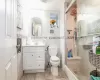 Bathroom with vanity, toilet, an enclosed shower, and tile walls