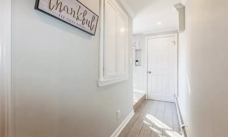 Hallway with light hardwood / wood-style flooring and a baseboard heating unit