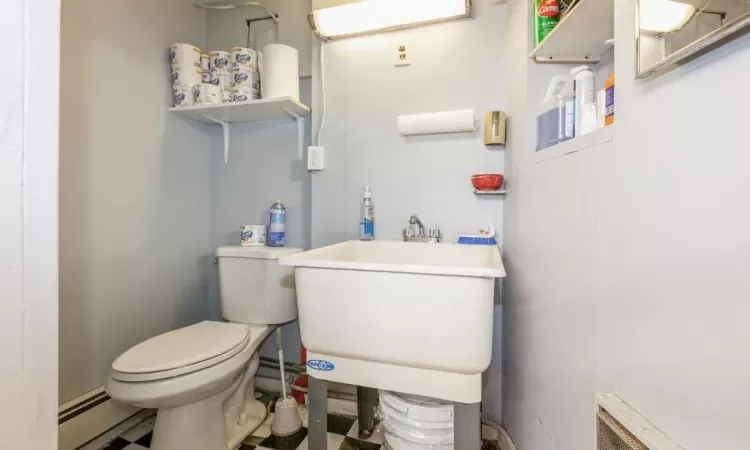 Bathroom featuring toilet, sink, and a baseboard heating unit