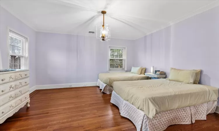 Bedroom featuring crown molding, dark hardwood / wood-style floors, and a chandelier