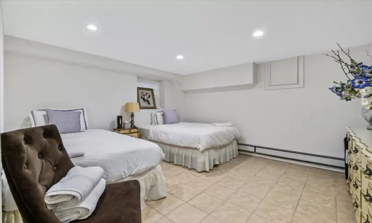 Bedroom with light tile patterned floors and baseboard heating