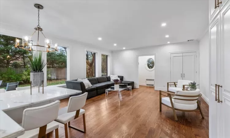 Living room with crown molding, radiator heating unit, a chandelier, and light hardwood / wood-style flooring