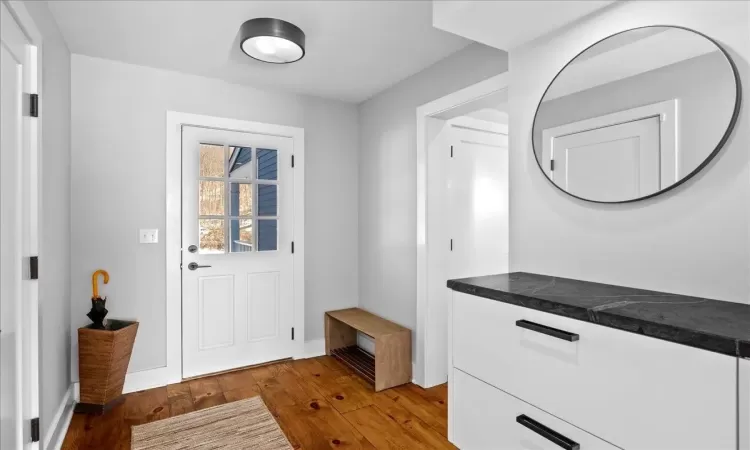 Washroom featuring hardwood / wood-style flooring and stacked washer and clothes dryer