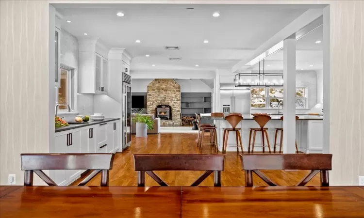 Kitchen featuring a center island, appliances with stainless steel finishes, white cabinets, decorative light fixtures, and wall chimney exhaust hood