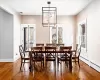 Dining room with wood-type flooring, a stone fireplace, and a notable chandelier