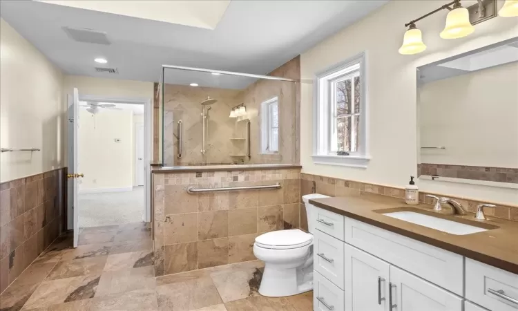 Bathroom featuring vanity, toilet, and tile walls