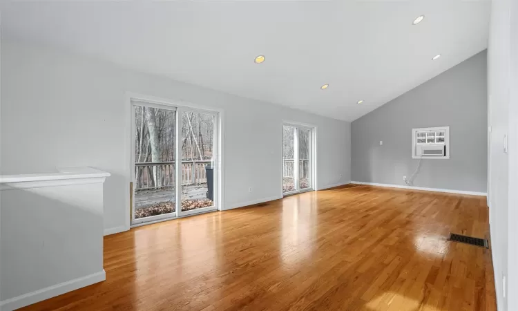 Unfurnished living room with light hardwood / wood-style floors and vaulted ceiling