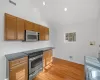 Kitchen with high vaulted ceiling, appliances with stainless steel finishes, and light wood-type flooring