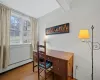 Office in lower level with beam ceiling, baseboard heating, and light hardwood / wood-style flooring