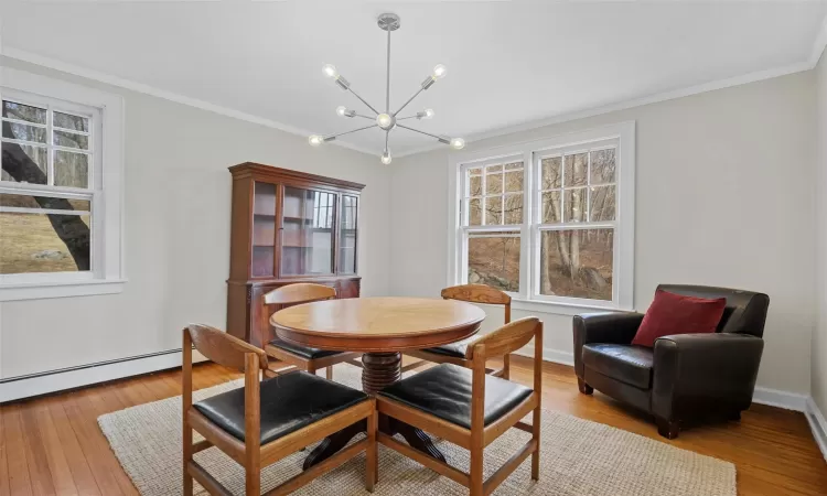 Dining space featuring baseboard heating, ornamental molding, light hardwood / wood-style flooring, and a notable chandelier