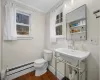 Bathroom featuring baseboard heating, hardwood / wood-style floors, toilet, and ornamental molding