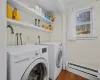 Clothes washing area featuring baseboard heating, dark hardwood / wood-style flooring, crown molding, and washing machine and clothes dryer