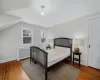 Bedroom with hardwood / wood-style floors, radiator heating unit, and lofted ceiling