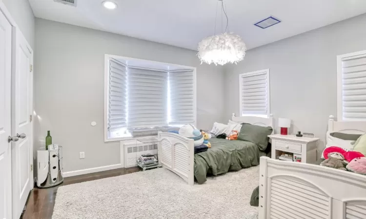 Bedroom with radiator, an inviting chandelier, and dark wood-type flooring