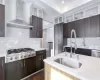 Kitchen with sink, decorative backsplash, wall chimney exhaust hood, and appliances with stainless steel finishes