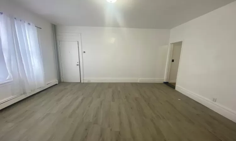 Living room featuring a wealth of natural light, wood-type flooring, and baseboard heating