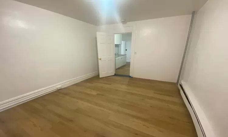 Bedroom with a baseboard heating unit and light wood-type flooring