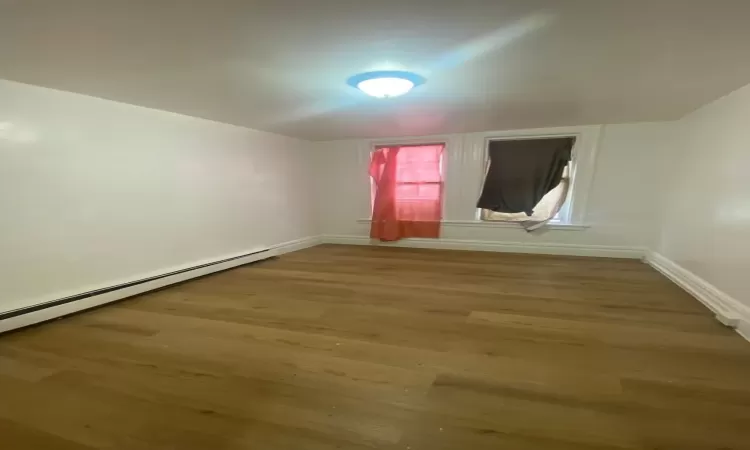 Bedroom with hardwood / wood-style flooring and baseboard heating