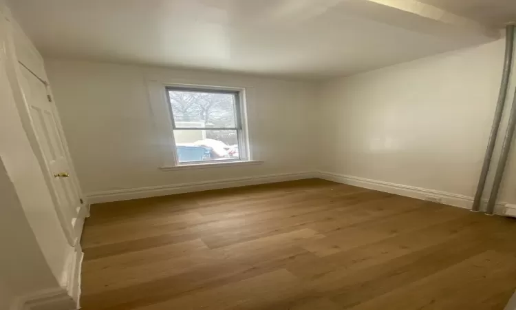 Unfurnished bedroom featuring a baseboard radiator, a closet, and light hardwood / wood-style flooring