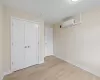 Unfurnished bedroom with a closet, light hardwood / wood-style flooring, and an AC wall unit