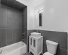 Full bathroom with tiled shower / bath, vanity, toilet, and tile walls