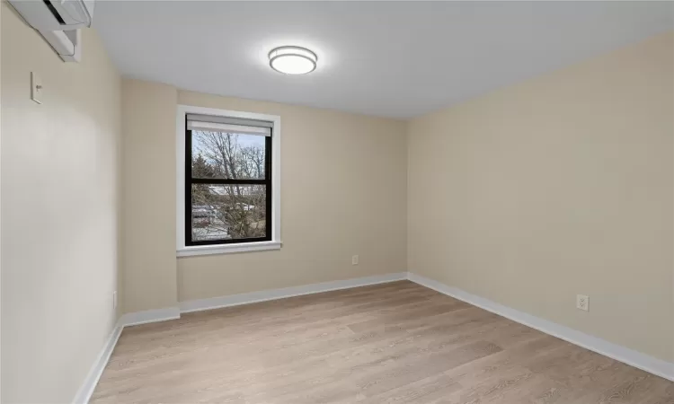 Empty room featuring a wall unit AC and light hardwood / wood-style flooring