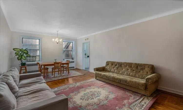 Living room featuring an inviting chandelier, parquet floors, and ornamental molding