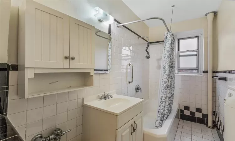 Bathroom with vanity, tile walls, tile patterned floors, and shower / bath combo with shower curtain