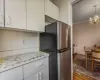 Kitchen featuring pendant lighting, white cabinetry, stainless steel fridge, dark hardwood / wood-style flooring, and an inviting chandelier