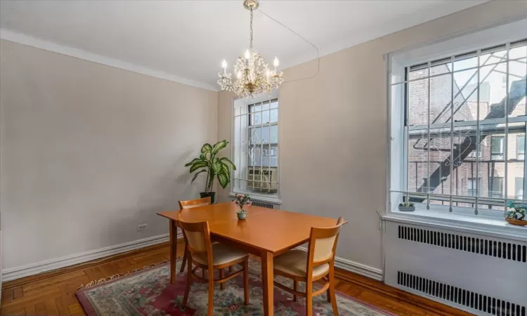 Dining room with parquet flooring, radiator, and an inviting chandelier