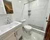 Bathroom with tiled shower, vanity, toilet, and tile walls