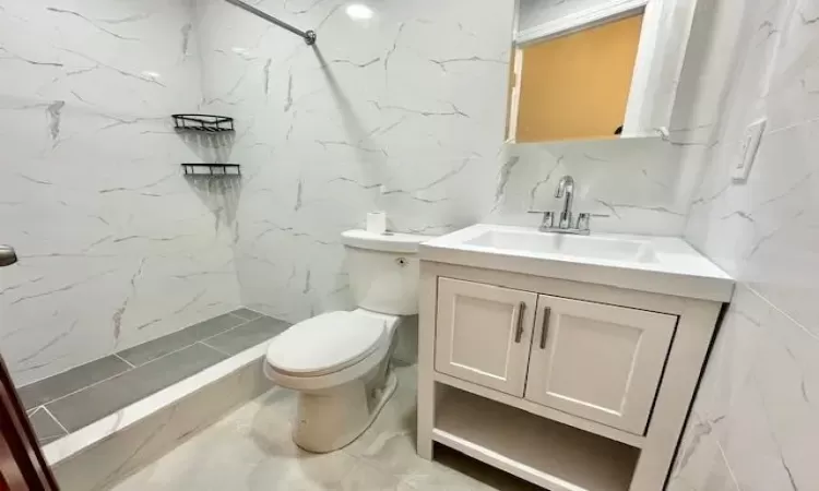 Bathroom with vanity, tiled shower, backsplash, and toilet