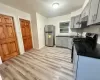 Kitchen with range with gas stovetop, stainless steel refrigerator, sink, gray cabinetry, and light hardwood / wood-style floors