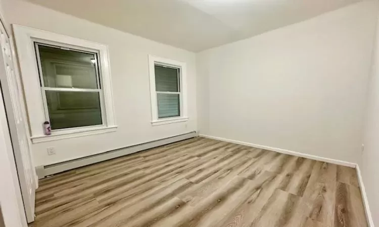 Spare room featuring a baseboard radiator and light hardwood / wood-style floors