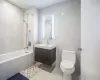 Full bathroom with tile patterned floors, toilet, tile walls, vanity, and tiled shower / bath combo