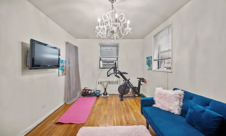 Workout area with cooling unit, hardwood / wood-style floors, radiator heating unit, and an inviting chandelier