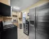 Kitchen with range with gas cooktop, tasteful backsplash, light tile patterned floors, stainless steel refrigerator with ice dispenser, and light brown cabinets