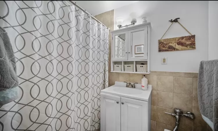 Bathroom featuring tile walls, vanity, and a shower with shower curtain